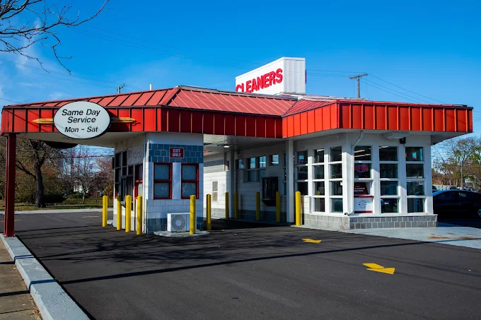 A drive-through dry cleaners with a red roof, white exterior, and signs advertising same day service from Monday to Saturday.